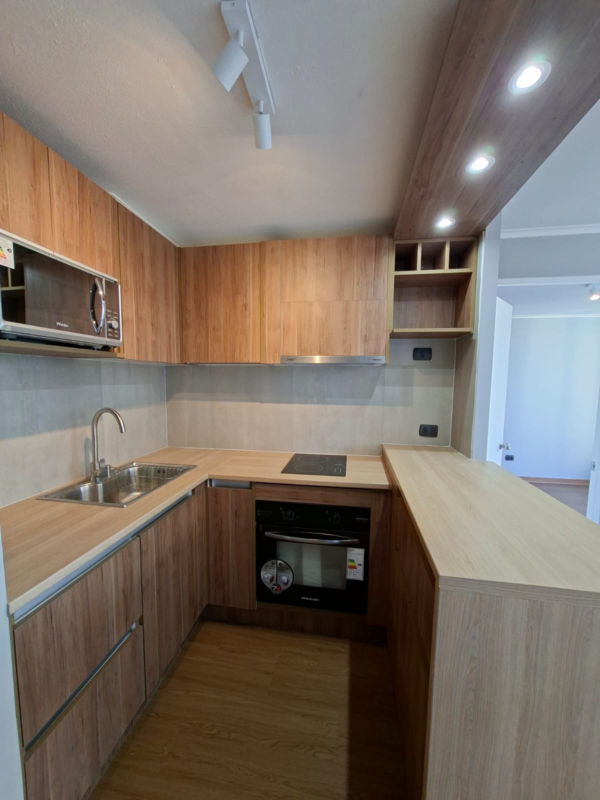 Cocina moderna en forma de U con muebles de madera clara